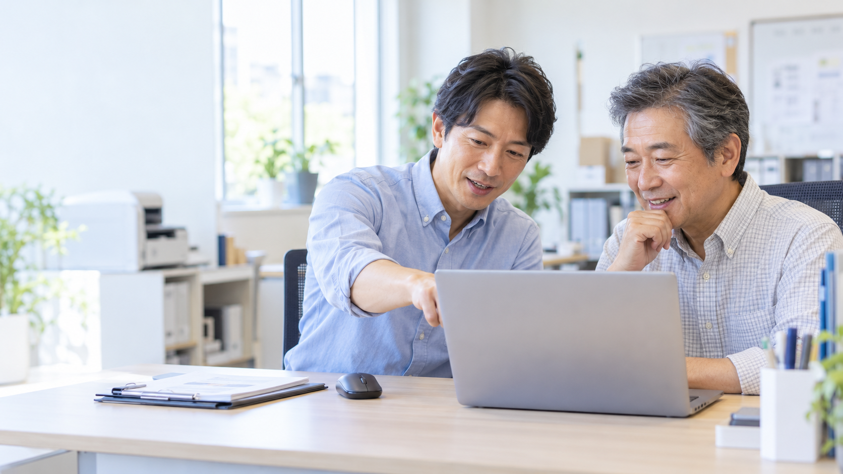 会社の事務所で、隣に座ってパソコンを確認する訪問ITサポートのイメージ